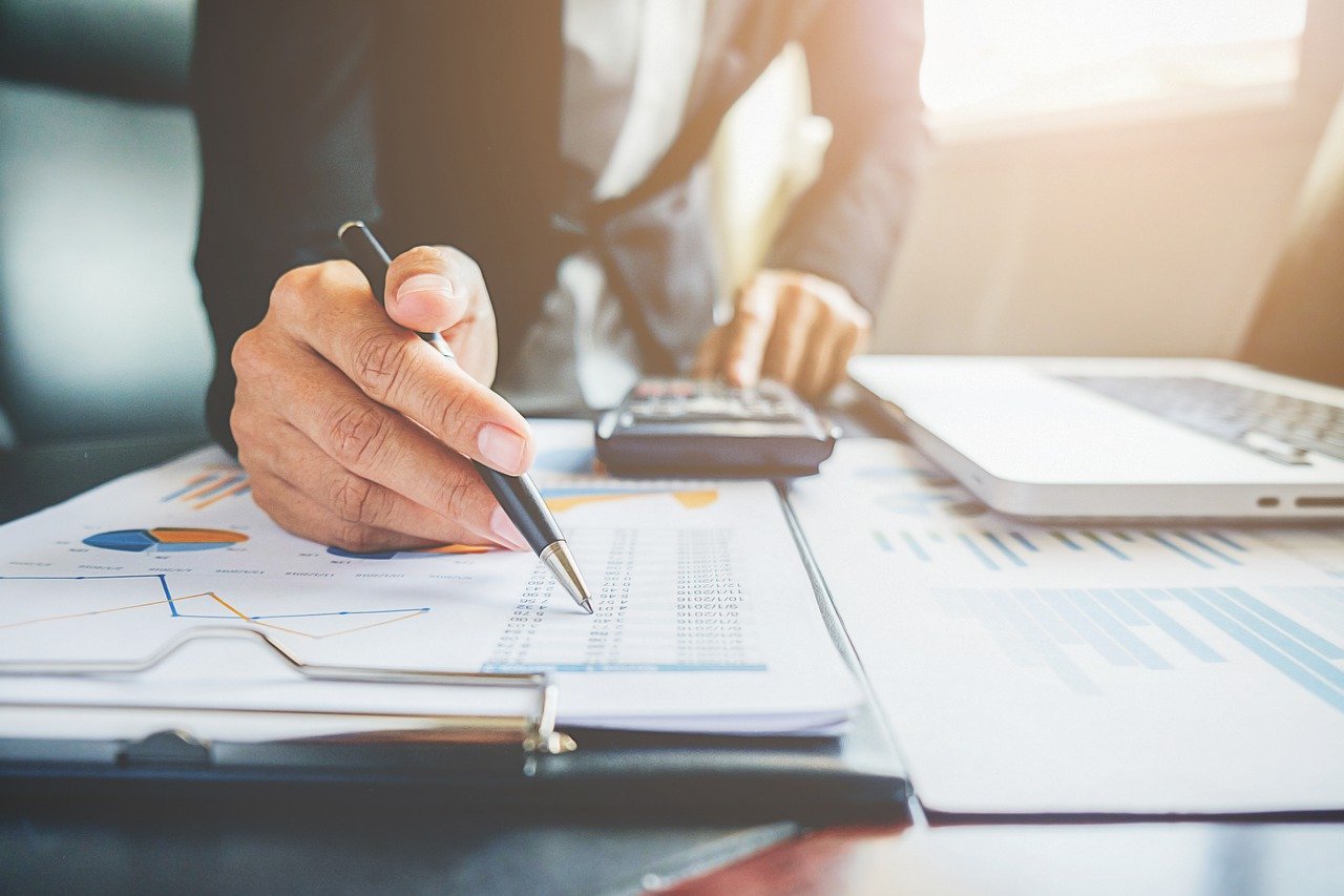 Close-up of a business professional analyzing financial charts and graphs, emphasizing the importance of estimated tax payments for self-employed individuals and those with additional income. Learn more at nxtgenfp.com.